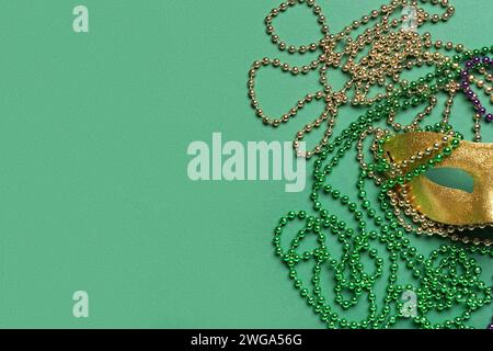 Perline colorate con maschera di carnevale per la celebrazione del martedì grasso su sfondo verde Foto Stock