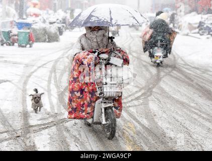 HUAI'AN, CINA - 4 FEBBRAIO 2024 - i cittadini viaggiano lentamente su una strada in una forte nevicata nella città di Huai 'an, provincia di Jiangsu, Cina, 4 febbraio 2024. Foto Stock