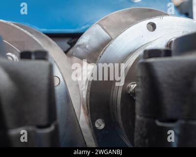 Astratto industriale. Alloggiamenti dei cuscinetti e viti di una pressa per viti doppie industriale. Profondità di campo molto bassa con le viti in acciaio inox in foc Foto Stock