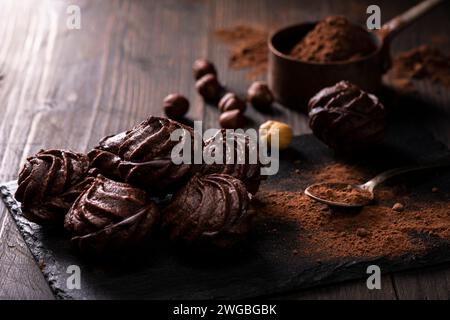 in primo piano, in un ambiente buio, baci al cioccolato con nocciole e cacao in polvere. Foto Stock