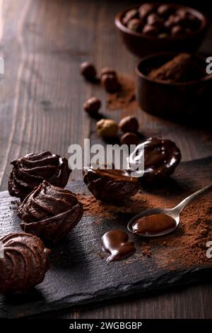 in primo piano, in un ambiente buio, baci al cioccolato con nocciole e cacao in polvere. Foto Stock