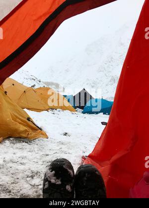 Donna in una spedizione di alpinismo seduta in una tenda, Himalaya indiana, India Foto Stock