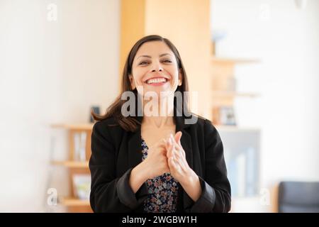 Ritratto di una donna sorridente in un ufficio che tiene il pugno Foto Stock