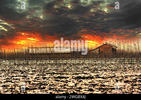 Tramonto spettacolare su due capanne accanto a un campo arato, Valmadonna, Alessandria, Piemonte, Italia Foto Stock