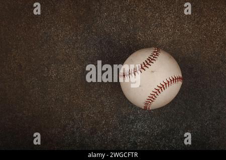Primo piano di una vecchia palla da baseball vintage indossata con punto rosso su sfondo marrone scuro grunge con spazio copia, vista dall'alto elevata, direttamente sopra Foto Stock