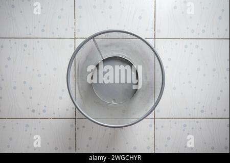 Vuoto del cestino di rifiuti in rete argentata sul pavimento della piastrella Foto Stock