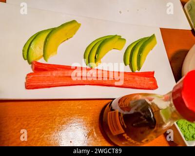 Preparatevi per condire sushi, avocado e bastoncini di granchio con salsa di soia Foto Stock