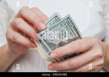 Primo piano di dollari americani in mano, conteggio delle banconote, sfondo chiaro. Concetto di finanza, affari, reddito. Foto Stock