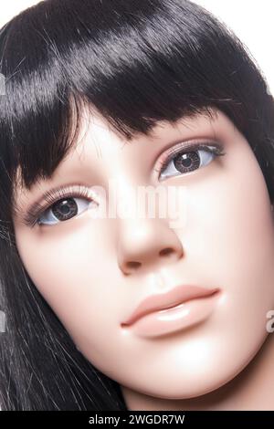 Primo piano di un manichino donna in plastica con capelli lunghi neri in posa su uno sfondo bianco in una configurazione di alto livello Foto Stock