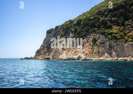 Isola rocciosa con alberi verdi a Keri durante la giornata estiva in Grecia. Bellissimo colore dell'acqua con Marathonisi a Zante. Scenario idilliaco in Europa. Foto Stock