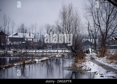 Srinagar, India. 4 febbraio 2024. Le persone camminano su un ponte innevato durante le nevicate. Le pianure del Kashmir stanno assistendo a una moderata nevicata, mentre nei tratti più alti della valle sono state segnalate forti nevicate. La valle del Kashmir ha subito una nevicata fresca che ha sconvolto la normale vita delle persone. Le operazioni di volo, il trasporto di superficie e le attività di routine della vita si arrestarono. (Immagine di credito: © Idrees Abbas/SOPA Images via ZUMA Press Wire) SOLO USO EDITORIALE! Non per USO commerciale! Foto Stock