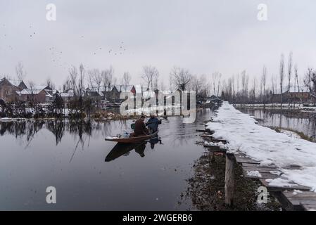 Srinagar, India. 4 febbraio 2024. Un uomo fila la sua barca sul lago dal durante le nevicate. Le pianure del Kashmir stanno assistendo a una moderata nevicata, mentre nei tratti più alti della valle sono state segnalate forti nevicate. La valle del Kashmir ha subito una nevicata fresca che ha sconvolto la normale vita delle persone. Le operazioni di volo, il trasporto di superficie e le attività di routine della vita si arrestarono. (Immagine di credito: © Idrees Abbas/SOPA Images via ZUMA Press Wire) SOLO USO EDITORIALE! Non per USO commerciale! Foto Stock