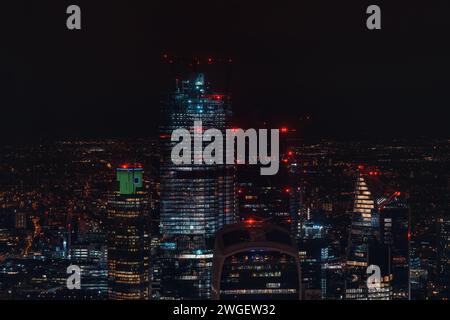 Vista aerea notturna dei grattacieli di Londra a Bishopsgate, torre incompiuta nel mezzo Foto Stock