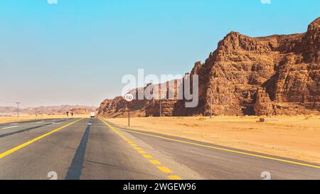 Strada panoramica nella regione di Alula in Arabia Saudita, deserto con formazioni rocciose sui lati, cielo limpido sopra Foto Stock