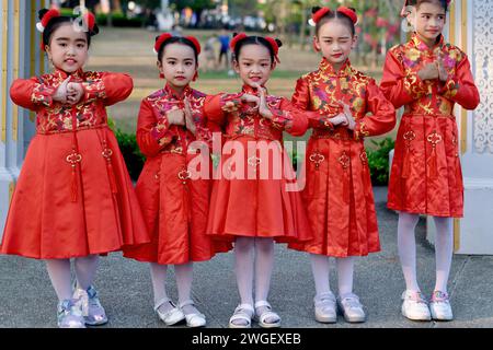 Giovani ragazze thailandesi-cinesi a Phuket, Thailandia, vestite con il tradizionale costume cinese rosso per il capodanno cinese, mostrando il gesto cinese del pugno nel palmo Foto Stock