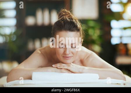 Il tempo dell'assistenza sanitaria. donna moderna e rilassata nel salone spa che si stende sul tavolo da massaggio. Foto Stock