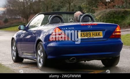 Milton Keynes, Regno Unito - 4 febbraio 2024: 2000 Mercedes Benz SLK blu, auto d'epoca open top, che guida su una strada inglese. Foto Stock