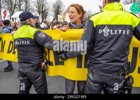 6 marzo 2014, l'Aia, Paesi Bassi: Attivista donna della ribellione per l'estinzione si ferma e si rifiuta di trasferirsi in una nuova linea di polizia, durante la manifestazione. La polizia ha rimosso 1.000 attivisti per il clima dalla A12 a l'Aia e li ha trasferiti allo stadio di calcio ADO a l'Aia, dove sono stati rilasciati. L'autostrada è stata bloccata in entrambe le direzioni da alcuni attivisti per il clima dalla ribellione dell'estinzione dalle 13:00, anche se erano presenti due canoni d'acqua, non sono stati utilizzati. Fu il primo blocco dell'A12 in quattro mesi. L'anno scorso, Extinction Rebellion ha bloccato la A12 diversi doze Foto Stock
