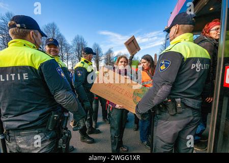 Gli attivisti della ribellione dell'estinzione sono scortati a un autobus in attesa, durante la manifestazione. La polizia ha rimosso 1.000 attivisti per il clima dalla A12 a l'Aia e li ha trasferiti allo stadio di calcio ADO a l'Aia, dove sono stati rilasciati. L'autostrada è stata bloccata in entrambe le direzioni da alcuni attivisti per il clima dalla ribellione dell'estinzione dalle 13:00, anche se erano presenti due canoni d'acqua, non sono stati utilizzati. Fu il primo blocco dell'A12 in quattro mesi. L'anno scorso, Extinction Rebellion ha bloccato l'A12 diverse dozzine di volte. Le loro azioni sono state sospese il 10 ottobre. La Casa dei Repres Foto Stock