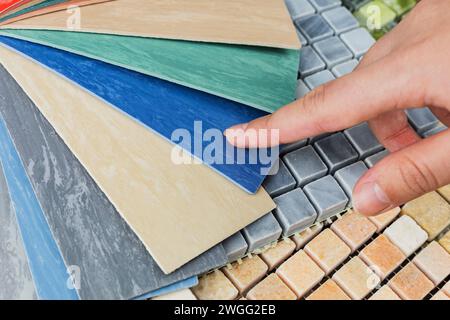 la mano del progettista che sceglie campioni di materiali in pietra per interni è costituita da piastrelle di cemento, pietre di quarzo, pietre artificiali, piastrelle grafiche. vista dall'alto dell'inter Foto Stock