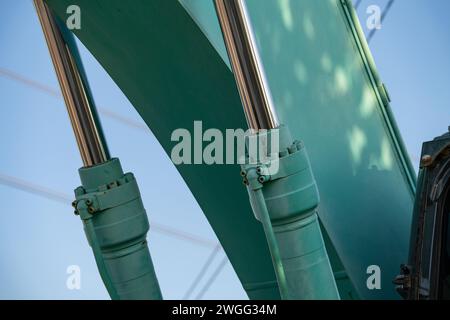 Vista ravvicinata del braccio idraulico in acciaio inox sull'escavatore verde. Potenza in acciaio inox nel braccio idraulico di un escavatore. Acciaio inossidabile Foto Stock