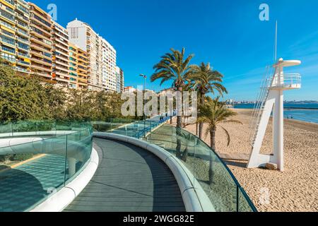 Vista dal ponte pedonale della passeggiata lungo gli edifici residenziali e la spiaggia con le palme sulla costa mediterranea di Alicante, Spagna. Foto Stock