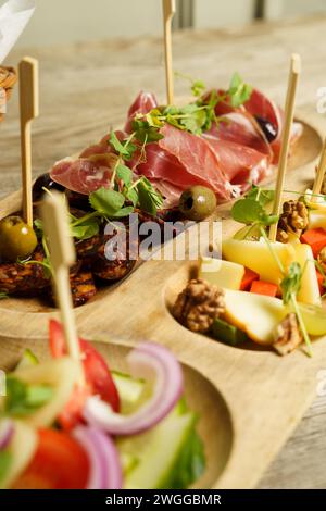 Selezione di prosciutto, formaggio locale, salsiccia chorizo e verdure su un piatto di legno Foto Stock