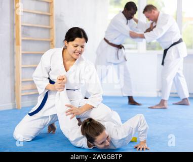 Ragazza che fa fuori la donna con jiu jitsu che si afferra per sottomissione in palestra Foto Stock