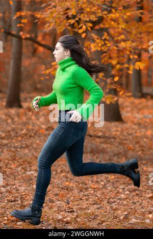 Donna che corre nella foresta per paura Foto Stock