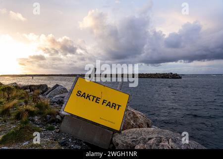 Insegna gialla sulla costa rocciosa con cielo nuvoloso Foto Stock