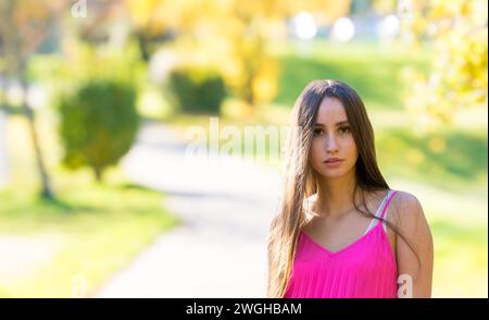 Giovane donna contemplativa con lunghi capelli castani e vestito giallo Foto Stock