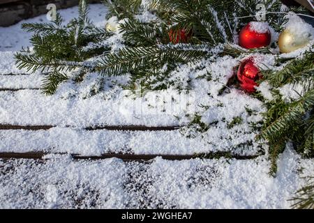 Baubles rosso dell'albero di natale con rami di abete e vera neve su tavole di legno Foto Stock