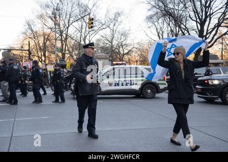 New York, Stati Uniti. 4 febbraio 2024. Un manifestante israeliano tiene la bandiera di Israele sopra la sua testa mentre viene scortato in un luogo diverso da un comandante della polizia di New York durante una marcia a sostegno della Palestina e contro l'applicazione da parte della polizia di New York delle leggi che impediscono ai dimostranti di utilizzare sistemi audio elettronici senza permesso. Credito: SOPA Images Limited/Alamy Live News Foto Stock