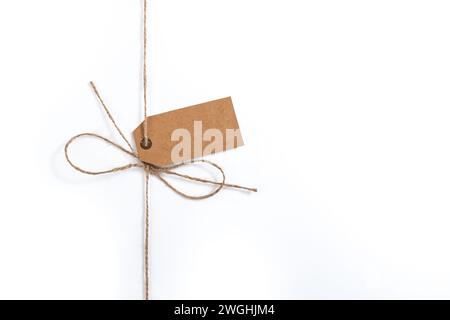 Filetto di iuta con arco semplice e etichetta vuota in cartone marrone isolata Foto Stock