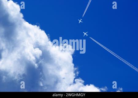 due aeroplani passeggeri con contrafforti in rotta di collisione nel cielo blu con nuvole Foto Stock