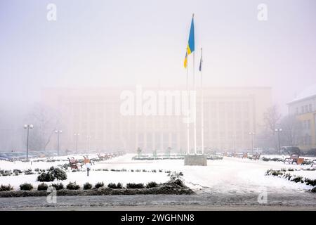 uzhhorod, ucraina - 26 GENNAIO 2017: Bandiere ucraine e dell'unione europea sulla piazza della narodna. paesaggio urbano in una mattina nebbiosa d'inverno. frosty e uncertai Foto Stock