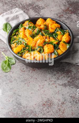 Aloo Palak sabzi Spinach patate al curry servito in un primo piano della ciotola sul tavolo. Verticale Foto Stock