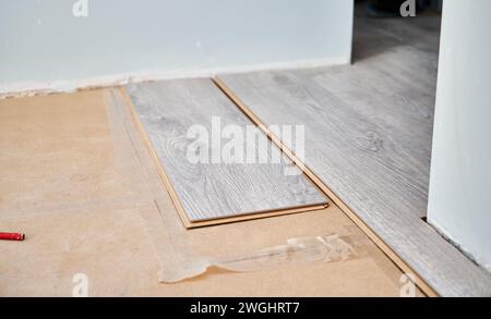 Pannelli laminati con motivo e struttura in legno per pavimenti e interni. Installazione di pavimenti in legno nell'appartamento in fase di ristrutturazione. Installazione di pavimenti in laminato e concetto di ristrutturazione della casa. Foto Stock