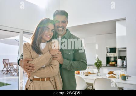 Una coppia matura felice che guarda la macchina fotografica in cucina a casa. Foto Stock