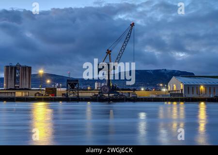 Una gru di carico e magazzini nel porto di Belfast al crepuscolo Foto Stock