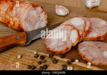 Involtino di pollo su un tagliere. Salsiccia di pollo. Stuzzicante polpettone su un asse di legno. Foto Stock