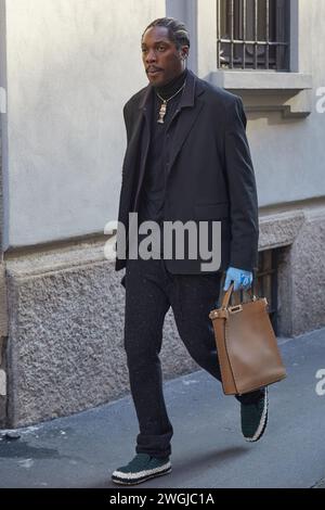 MILANO, ITALIA - 15 GENNAIO 2024: Uomo con giacca nera, pantaloni e borsa in pelle marrone prima della sfilata di Giorgio Armani, Milano Fashion Week Street Foto Stock