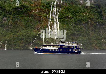 Le cascate e la nave da crociera Fiordland Navigator si aprono in una giornata di pioggia a Doubtful Sound / Patea, Fiordland /te Rua-o-te-Moko, nuova Zelanda / AOT Foto Stock