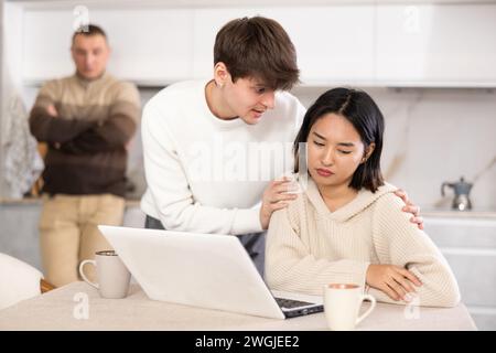 Un ragazzo convince una giovane ragazza a smettere di giocare ai videogame. Padre turbato in sottofondo Foto Stock