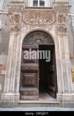 Bella porta in legno intagliato su un primo piano ad arco in marmo. Esterno dell'edificio, facciata a Lucca, italia Foto Stock