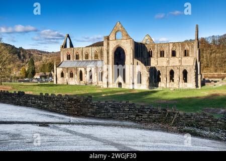 Abbazia di Tintern nella valle di Wye a Monmouthshire, regno unito in una giornata di inverni soleggiati con gelo in zona ombreggiata e cielo blu dietro Foto Stock