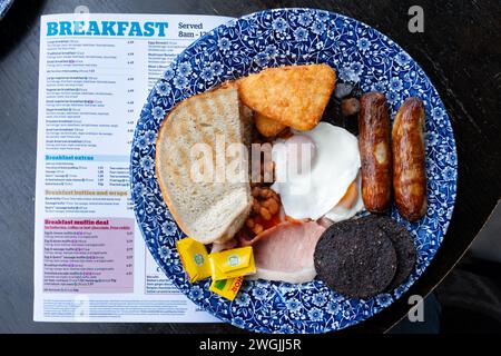 Una grande colazione Wetherspoons servita in un pub Wetherspoons. La colazione è di 1286 calorie. Il menu della colazione da pub è a lato del piatto Foto Stock
