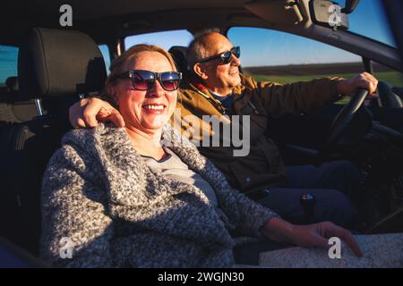 Una coppia di anziani sorridente che guida un'auto. Foto Stock