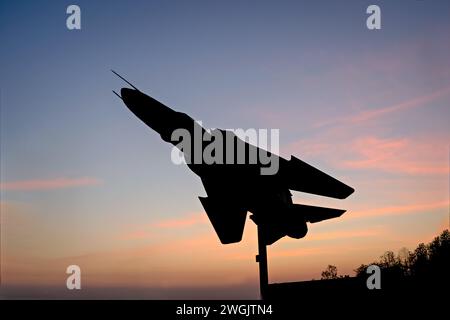 Il sole sorge dietro l'immagine della silhouette dell'aereo da caccia MIG-29 dell'Indian Air Force esposto al NDA Chowk di Pune. Foto Stock