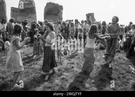 Hippy Counter culture anni '1970 Regno Unito. Stonehenge Free Festival al solstizio d'estate degli anni '1970 Un piccolo gruppo di hippy New Age, un gruppo di famiglia ballano e festeggiano insieme mentre altri guardano. Wiltshire, Inghilterra, 21 giugno 1979. HOMER SYKES anni '70 Foto Stock